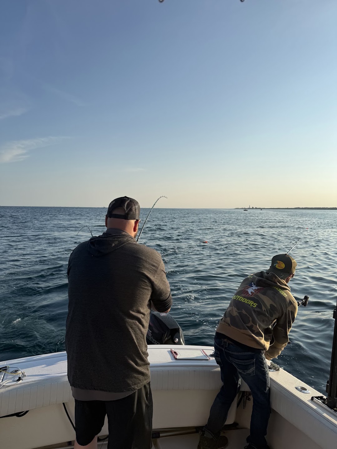 Two anglers trolling on calm Lake Michigan water in the evening light