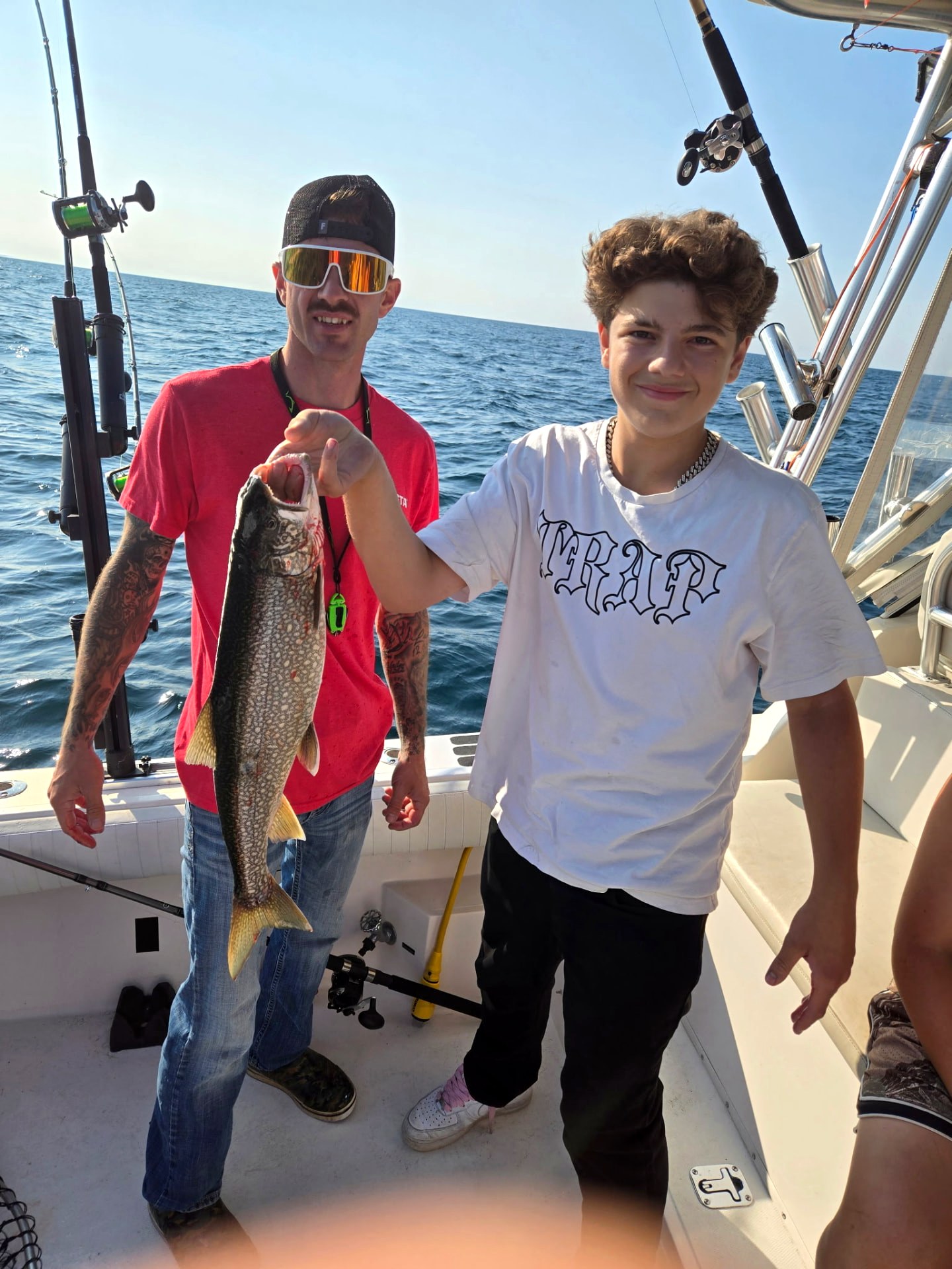 Captain and young angler holding a Lake Michigan lake trout