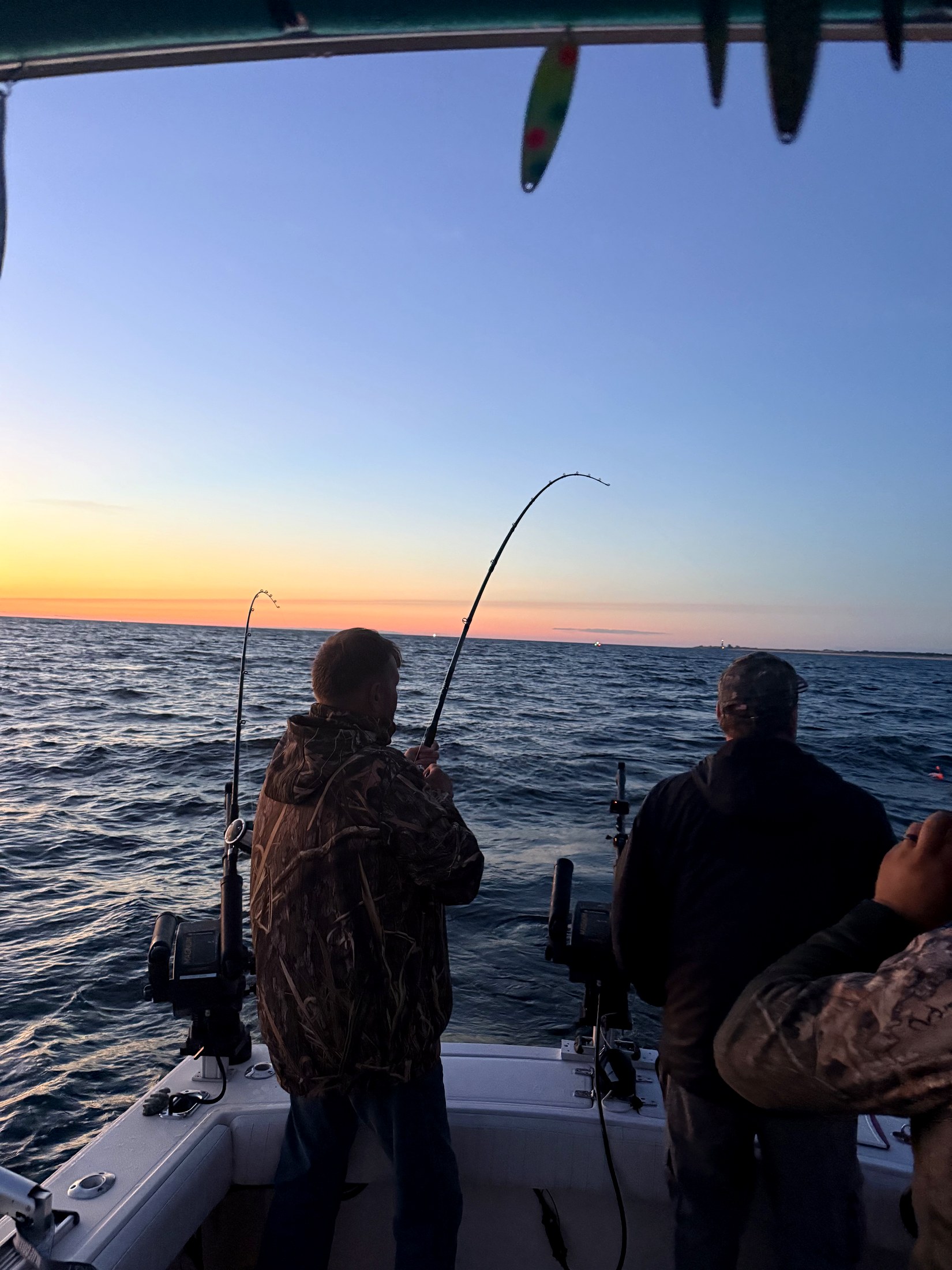 Rods bent at sunset off Ludington with the lighthouse on the horizon