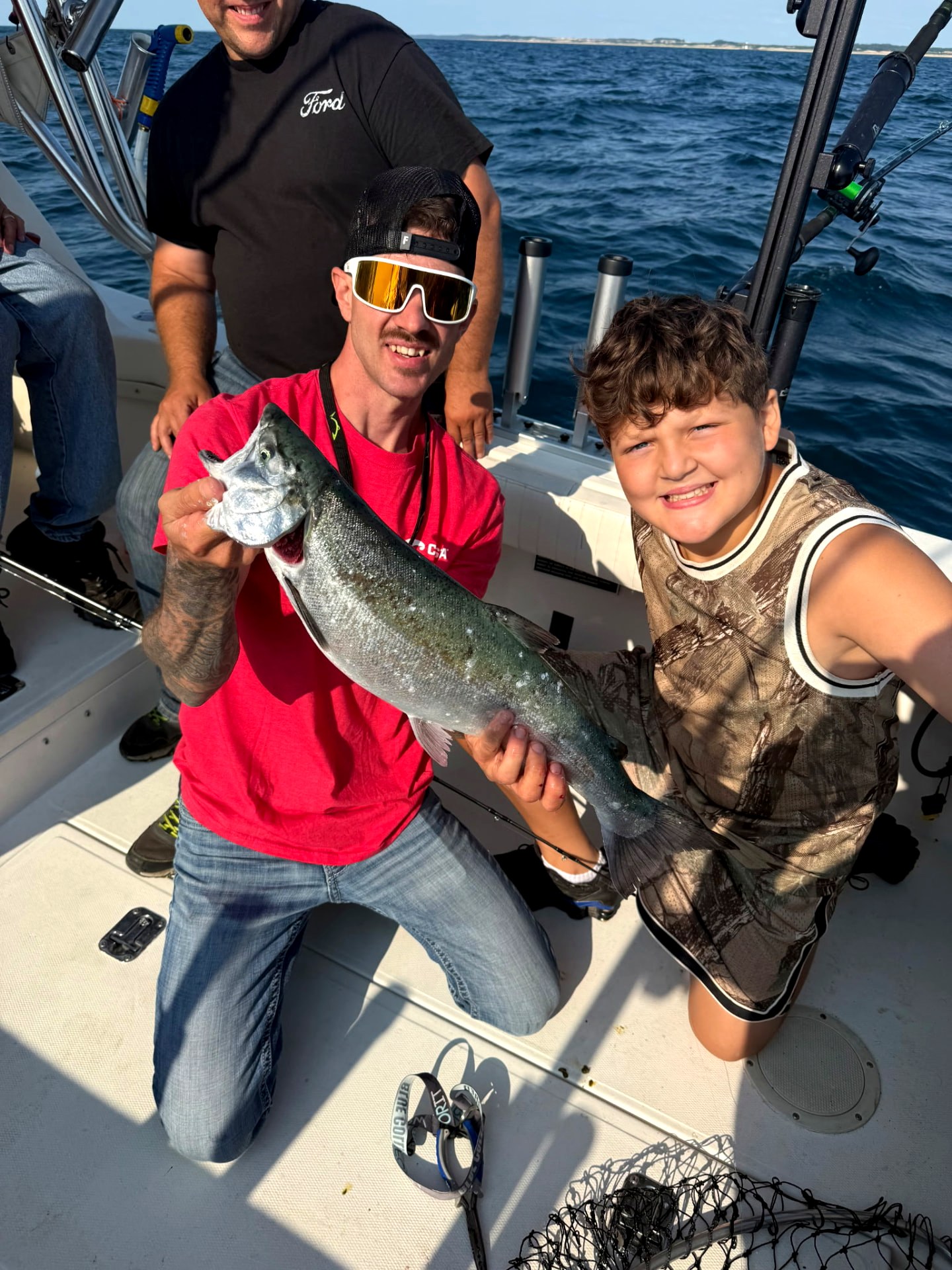 Captain and young angler hoisting a Lake Michigan king salmon