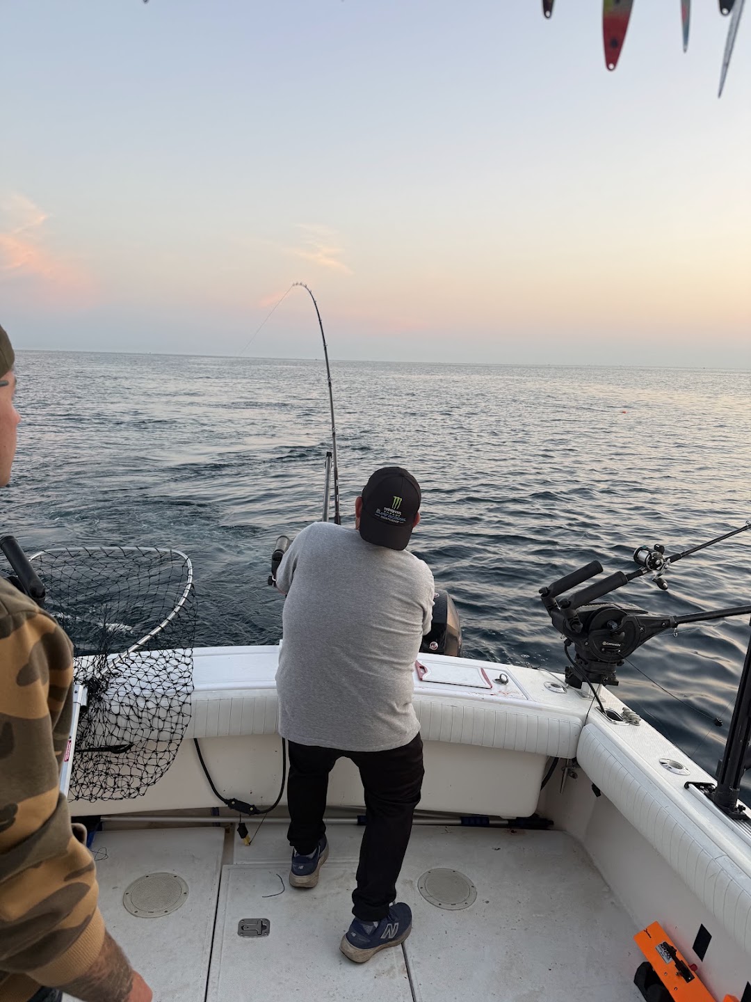 Angler fighting a salmon from the back of a charter boat on Lake Michigan