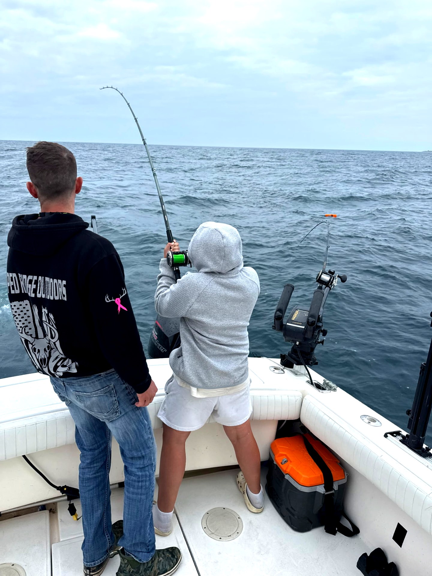 Angler working a downrigger rod on an overcast Lake Michigan morning
