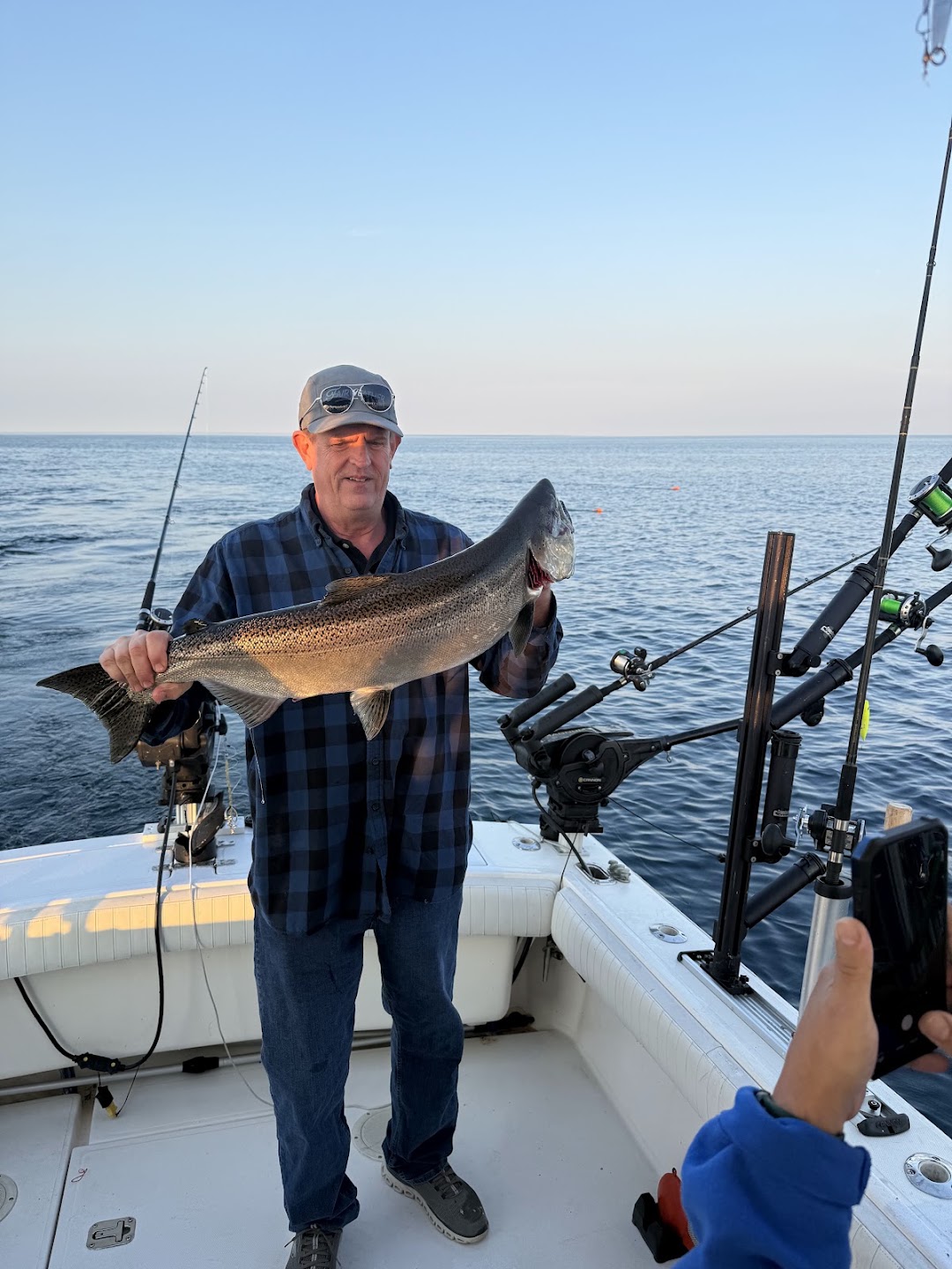 Guest holding a large Lake Michigan salmon on the charter boat at sunset