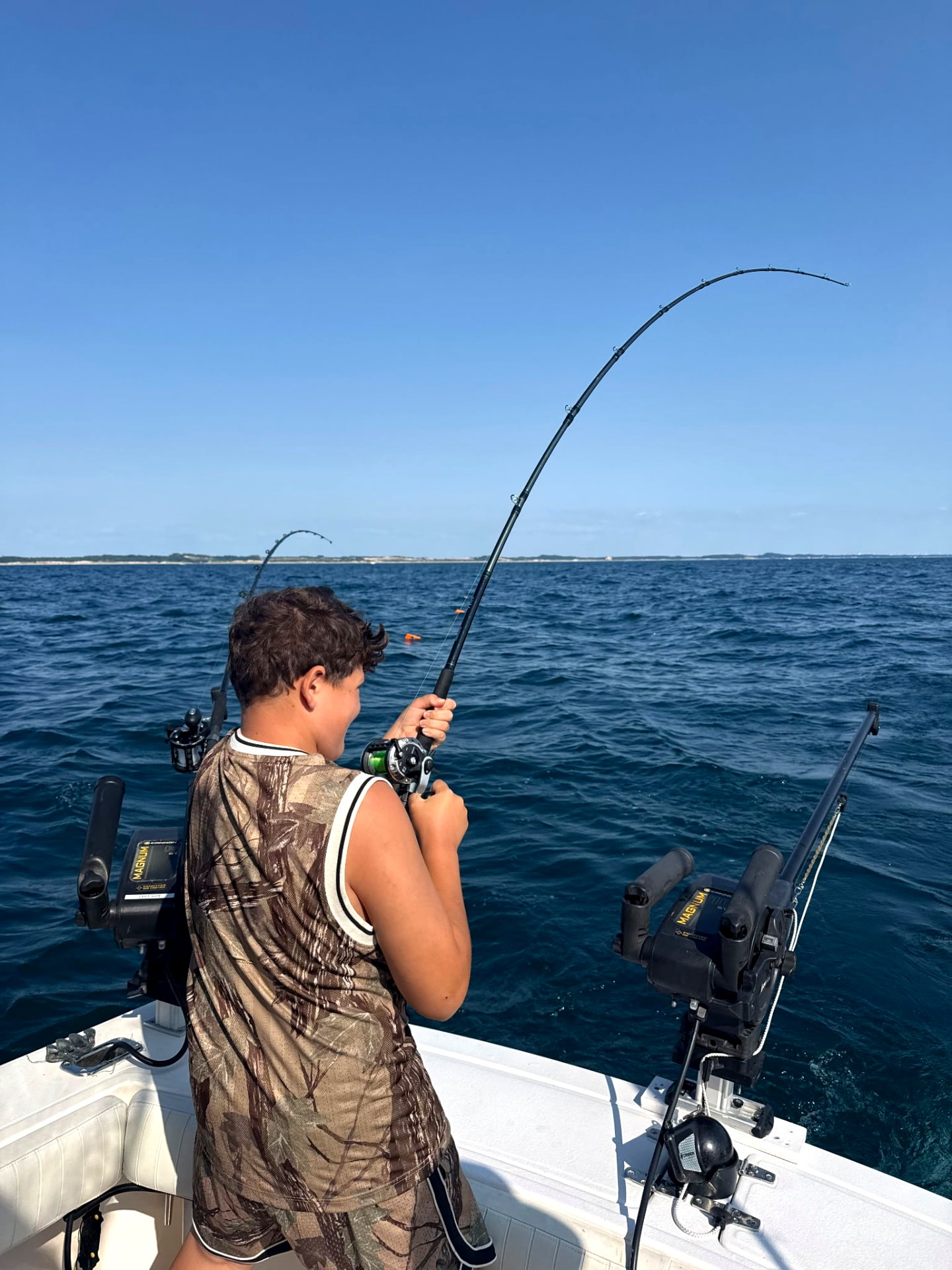 Young angler fighting a salmon on a bent rod off Ludington