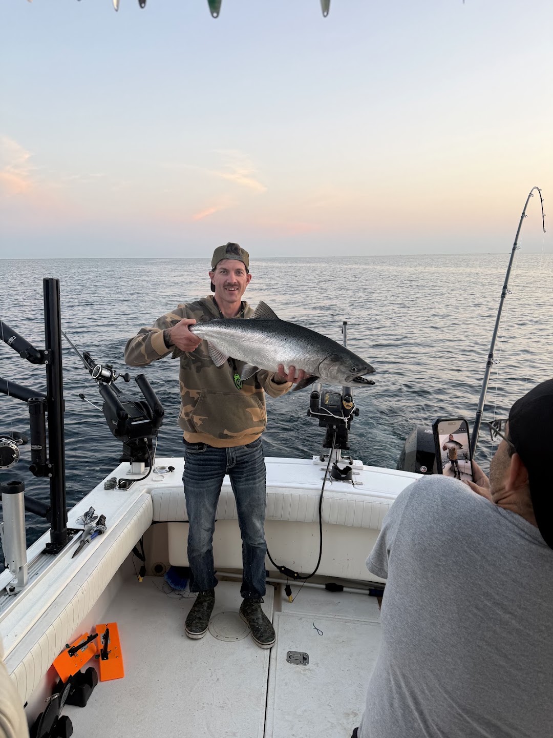 Guest holding a chrome king salmon on the deck of the charter boat at sunset