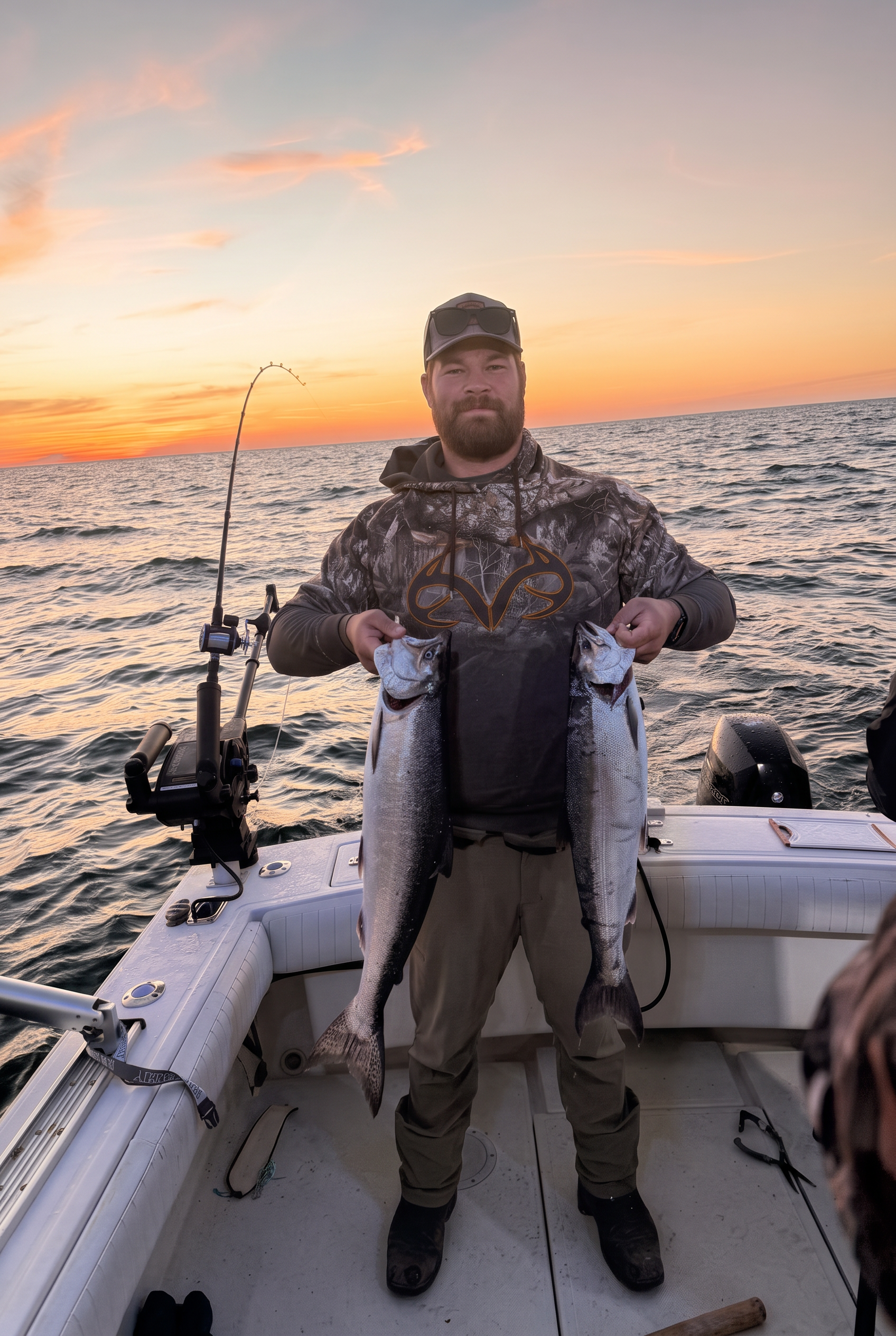 Angler holding two king salmon at sunset on Lake Michigan